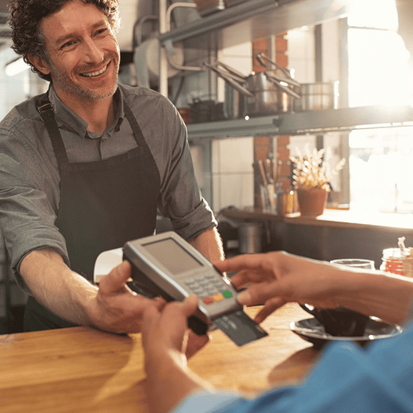 Man holding counter service payments device for customer to insert payment card.