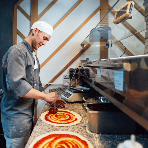 Pizza Epos: Male pizza chef preparing two pizzas.