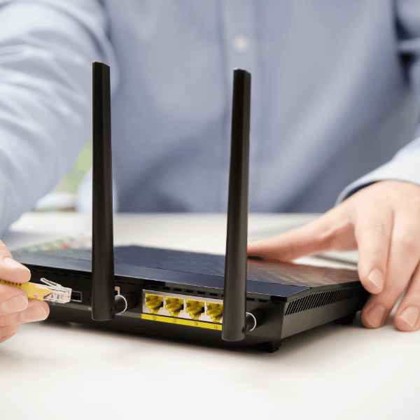 Man inserting patch cable into broadband router port.